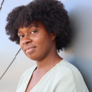 Uma mulher encostada na parede com um olhar confiante