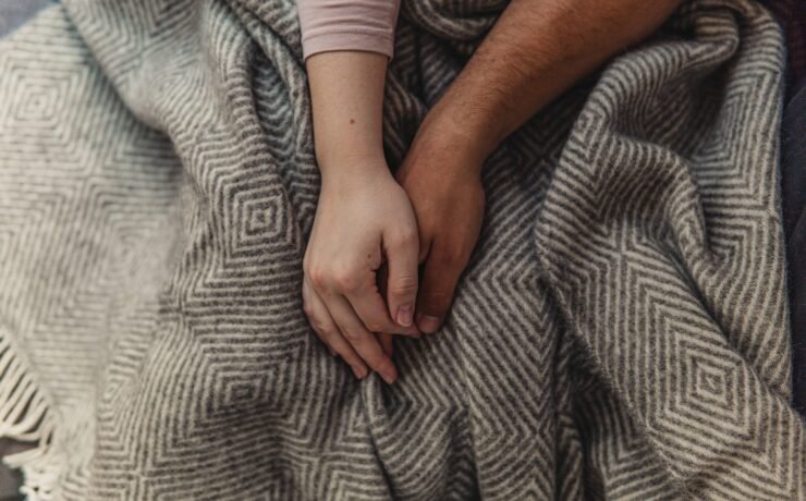 two people in bed holding hands