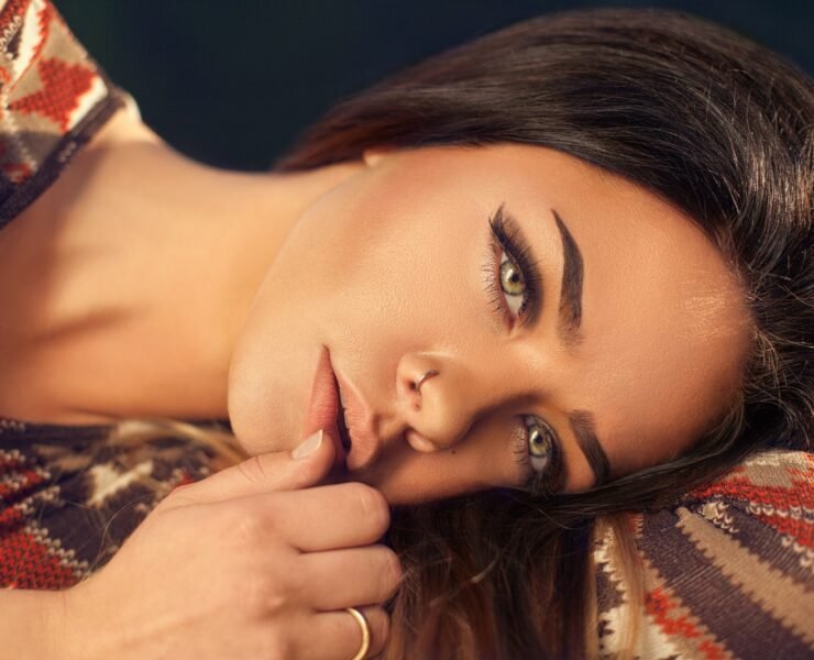 woman lying down with hand near mouth wearing nose ring