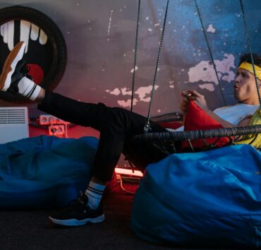 Man playing Games while sitting on a Hanging Chair