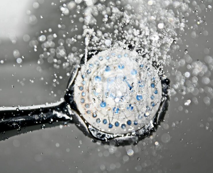 Close-up of a shower head releasing water droplets, creating a crisp and refreshing bathroom scene.