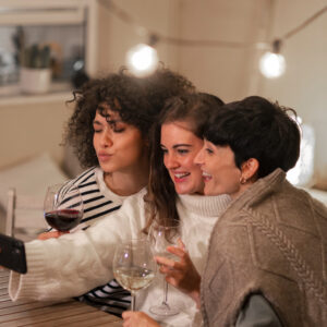 três mulheres tomando vinho e se divertindo