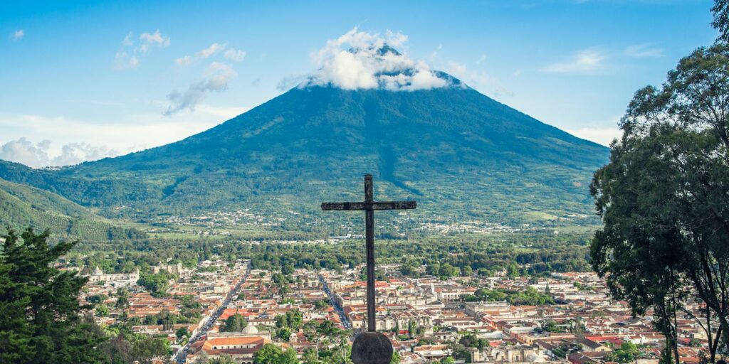 Vista panorâmica de Antígua, Guatemala, com o Vulcão de Água, com uma cruz proeminente em primeiro plano.