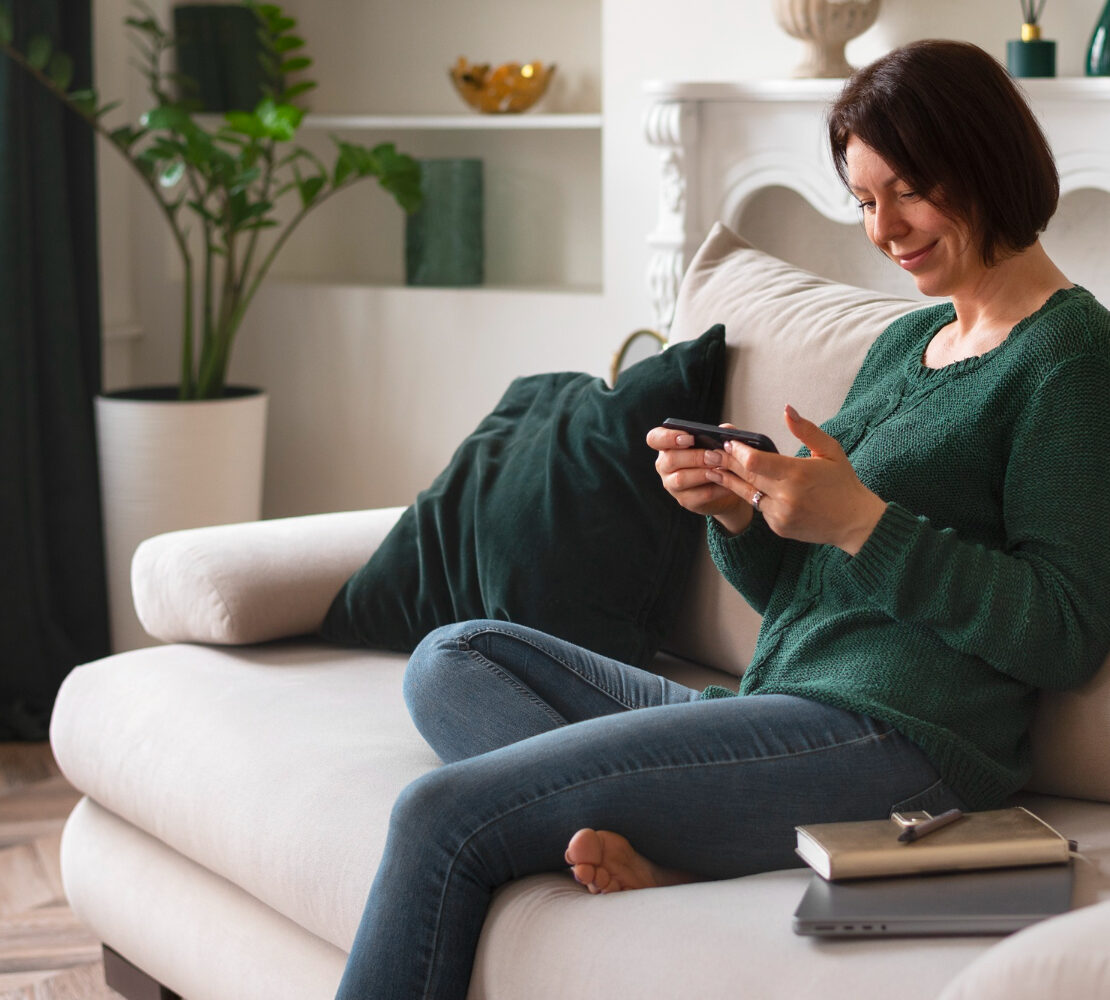 mulher sentada no sofá olhando para um smartphone