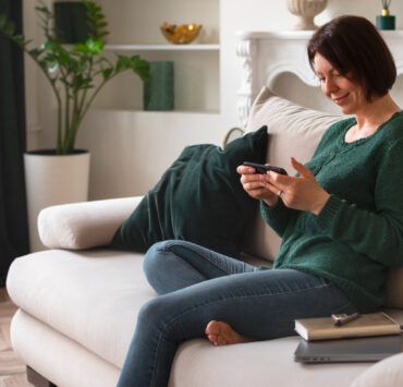 mulher sentada no sofá olhando para um smartphone