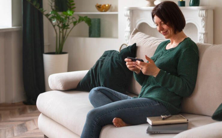 mulher sentada no sofá olhando para um smartphone