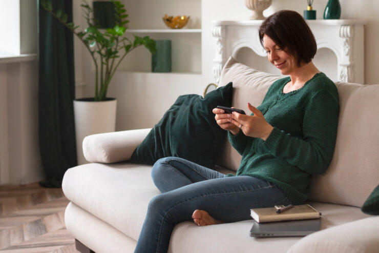 mulher sentada no sofá olhando para um smartphone