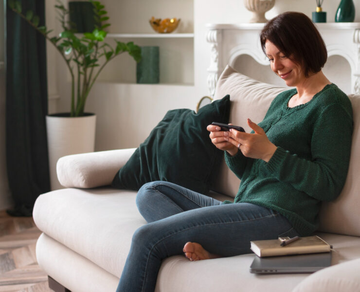 mulher sentada no sofá olhando para um smartphone