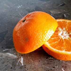 A vibrant, freshly cut orange revealing its juicy segments on a marble surface.