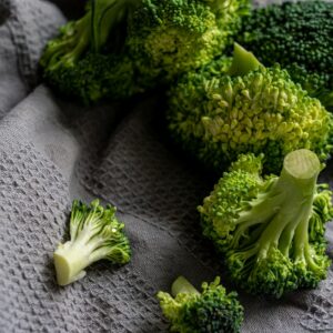 Vibrant green broccoli florets displayed on a gray textured cloth for a fresh, organic feel.