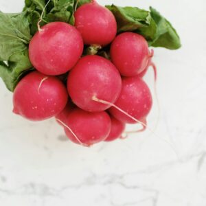 Close-up of fresh red radishes on a marble countertop, showcasing their vibrant color and natural texture.