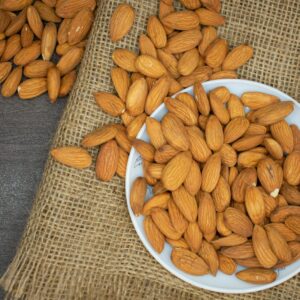 Top view of almonds in a white bowl on a burlap surface, highlighting healthy snacking.