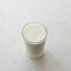 A top-down view of a foamy glass of milk on a white marble surface. Perfect for a healthy lifestyle concept.