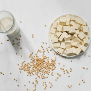 Top view of tofu cubes, soybeans, and soy milk on a white background – perfect for vegan food themes.