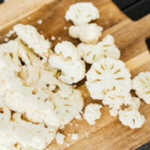 Slices of fresh cauliflower on a wooden cutting board, perfect for cooking and healthy recipes.