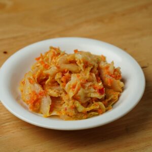Savory Korean kimchi served in a classic white ceramic bowl on a wooden table.