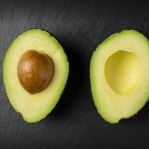 Close-up of fresh sliced avocado halves on a dark slate surface, showcasing healthy eating.