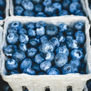 Close-up of fresh organic blueberries in cardboard trays at a market, showcasing their vibrant blue color and ripe appearance.