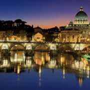 Hermosa vista de la Basílica de San Pedro y el Puente de San Ángel en Roma al atardecer reflejándose en el río Tíber.