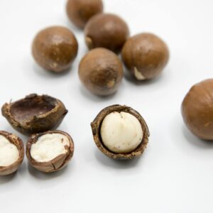 Detailed view of raw macadamia nuts showing whole and open shells on a white background.