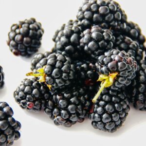 A vibrant close-up of fresh blackberries on a white background, highlighting their juicy texture.