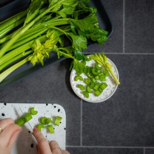 a person chopping celery on a cutting board