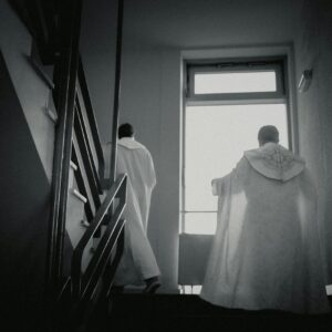 a couple of men standing next to each other near a window