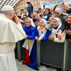 Pope Francis standing surrounded with people