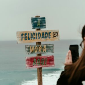 mulher fotografando uma placa com celular, a felicidade mora aqui