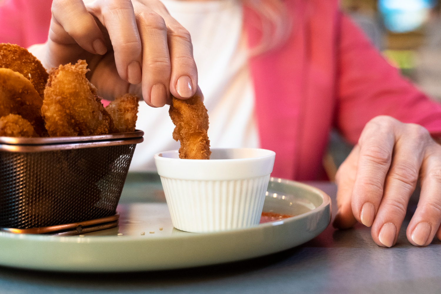 mulher molhando nuggets de frango em molho