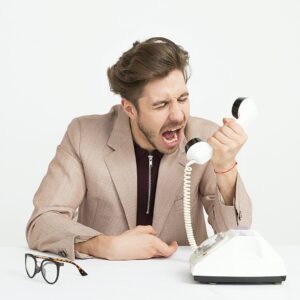 homem nervoso segurando um telefone e gritando