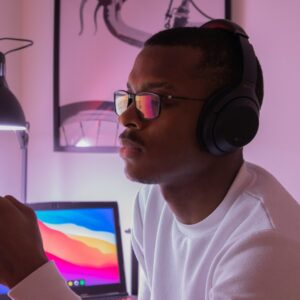 homem em frente a um computador distraido com um smartphone e fones de ouvido