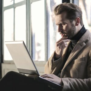 homem pensativo com um laptop no colo