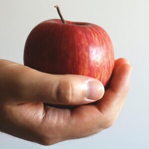 Close-up image of a hand holding a ripe red apple, emphasizing freshness and healthy eating.