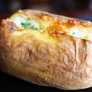 batata assada recheada sobre um prato escuro
