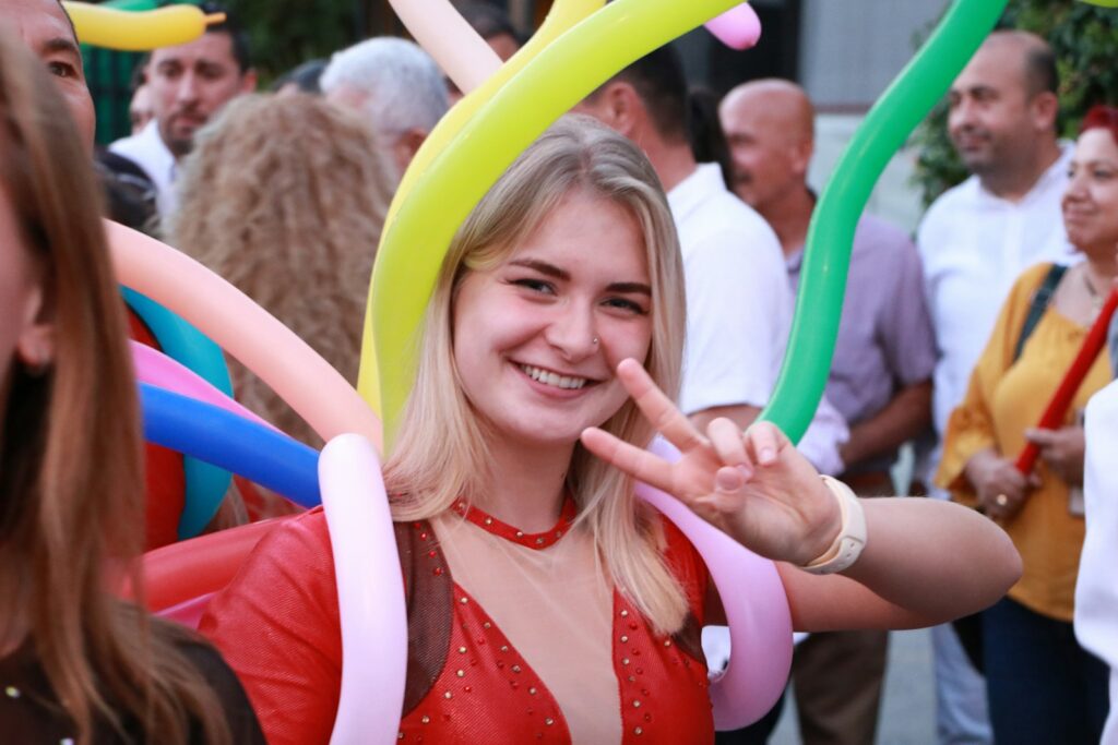 A woman smiles with balloons at an event.