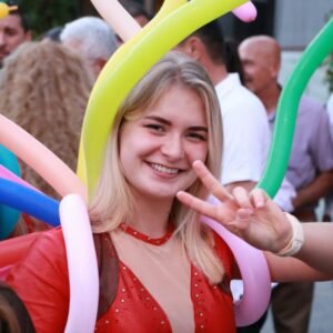A woman smiles with balloons at an event.