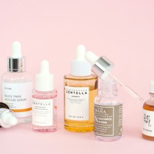 Skincare products, including serums, arranged on pink.