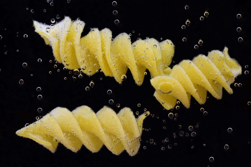 três pedaços de macarrão fusilli mergulhados na água