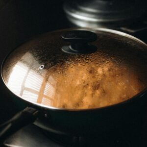Close de uma panela fumegante com tampa no fogão ilustrando o ambiente da comida caseira.