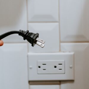 pessoa desconectando um plug preto da tomada