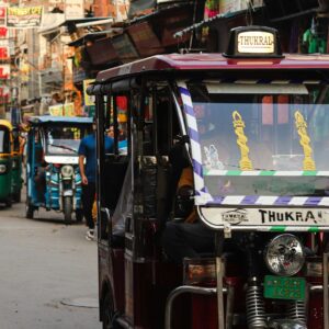 Um tuk tuk dirigindo por uma rua movimentada, Delhi, Índia
