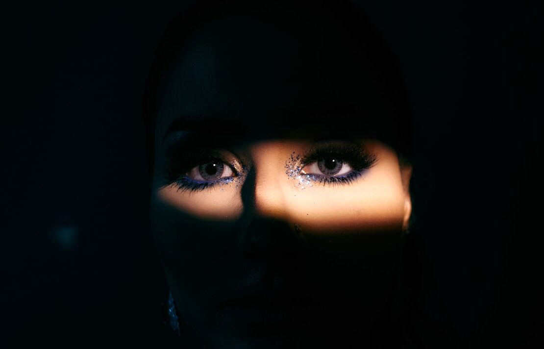 o rosto de uma mulher é iluminado pela luz de uma lanterna mostrando os olhos