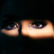 o rosto de uma mulher é iluminado pela luz de uma lanterna mostrando os olhos