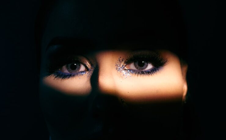 o rosto de uma mulher é iluminado pela luz de uma lanterna mostrando os olhos