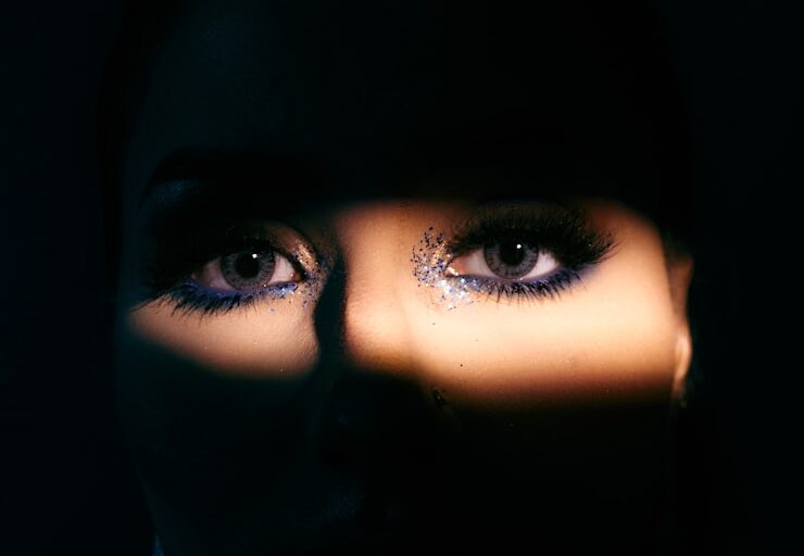 o rosto de uma mulher é iluminado pela luz de uma lanterna mostrando os olhos