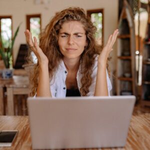 mulher surpresa e irritada em frente a um laptop