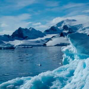 um grande iceberg flutuando no topo de um lago cercado por montanhas cobertas de neve