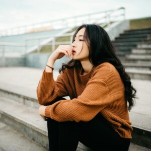 mulher vestindo suéter marrom segurando os lábios