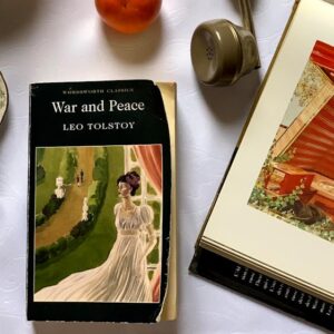Elegant overhead shot of a vintage tea set with classic literature and assorted items on a white background.